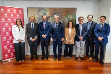 Ocho profesionales posan en fila frente a un cuadro y junto a un roll‑up de Universidad Complutense tras un acto institucional.