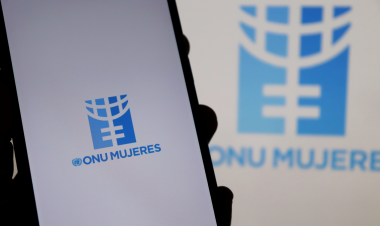 Logotipo de ONU Mujeres en pantalla de un móvil, con versión ampliada y desenfocada del mismo fondo.