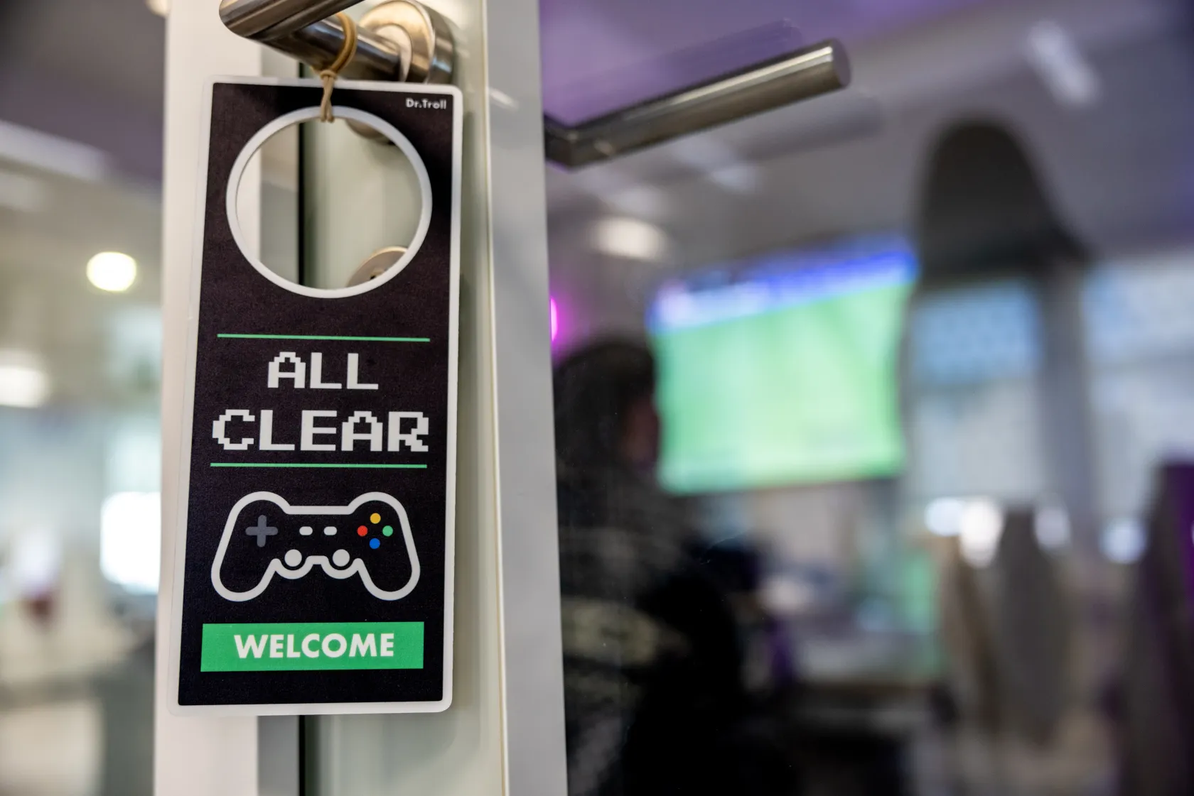 Fotografía del cartel colgado en el pomo de la puerta de la sala gamer, que da la bienvenida a los jugadores 