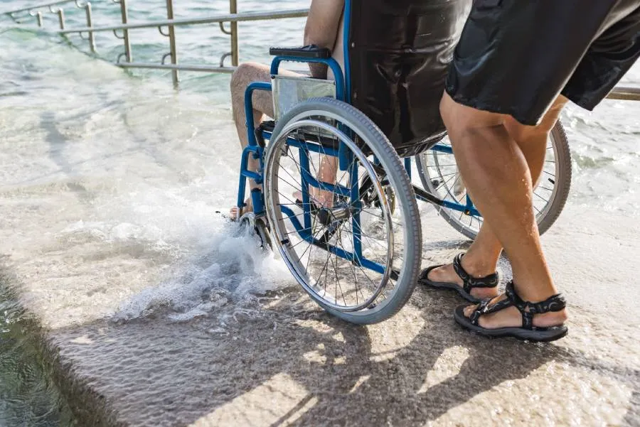 Chico en silla de ruedas accediendo por una rampa accesible a la playa