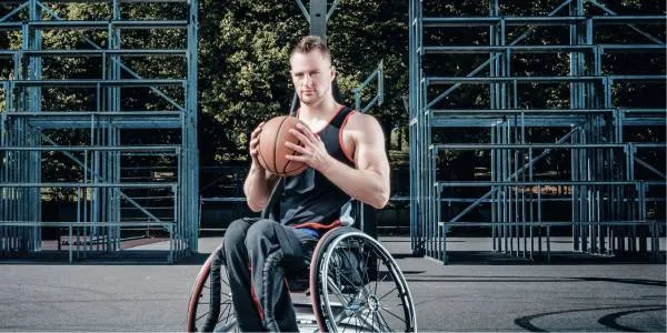 Chico en silla de ruedas con un balón de baloncesto en las manos.