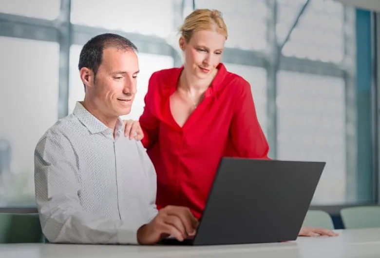 Un hombre y una mujer, profesionales en seguros de asistencia en viaje, mirando un portátil