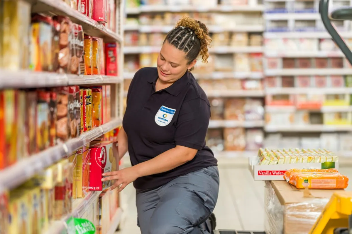 Trabajadora de ILUNION está reponiendo un lineal de supermercado