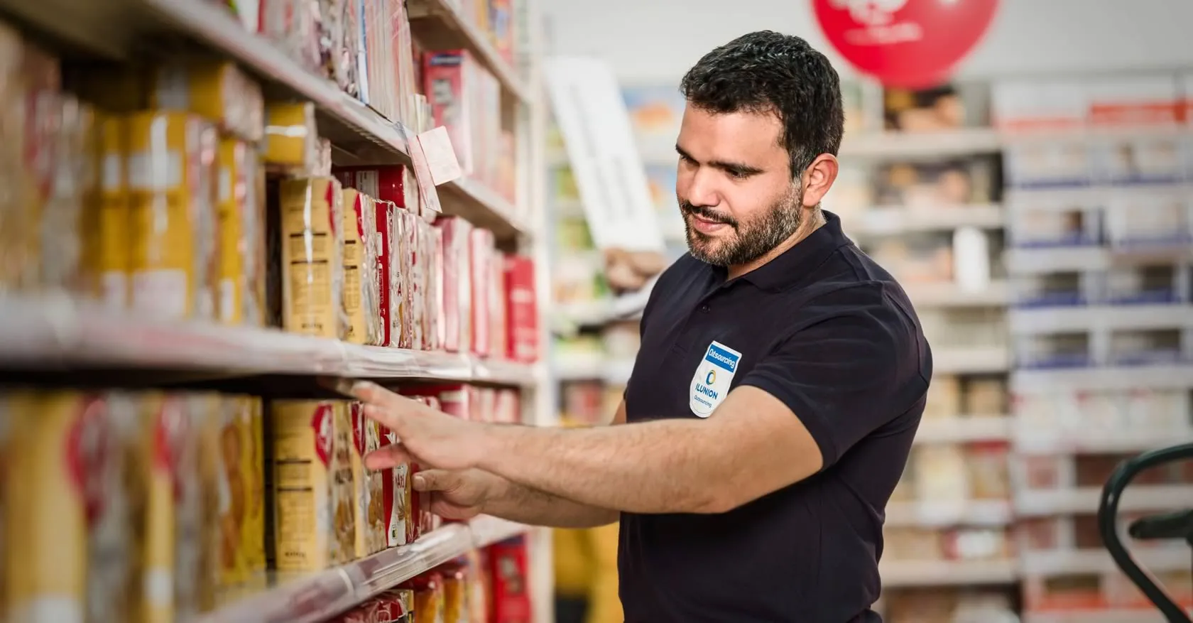 Empleado de ILUNION está reponiendo el lineal de un supermercado