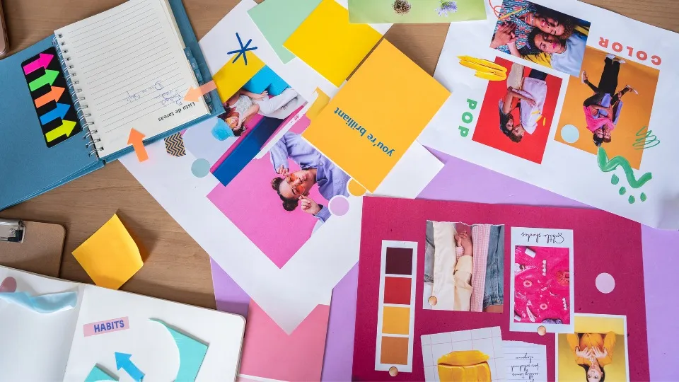 Un espacio de trabajo creativo con tableros de inspiración coloridos, notas adhesivas y un cuaderno con garabatos. El ambiente es vibrante e inspira la lluvia de ideas.