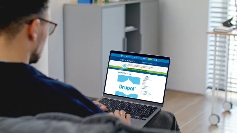 Hombre sentado enfrente de su ordenador trabajando con Drupal.