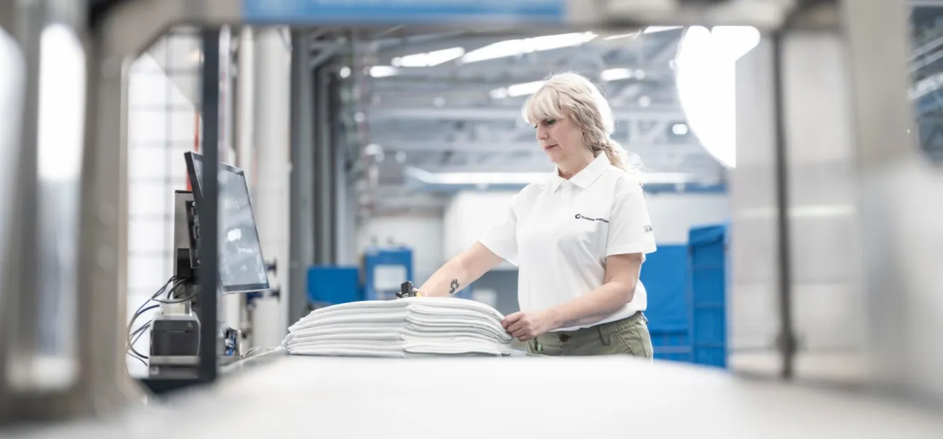 Se muestra a una trabajadora de ILUNION TextilCare manipulando textil