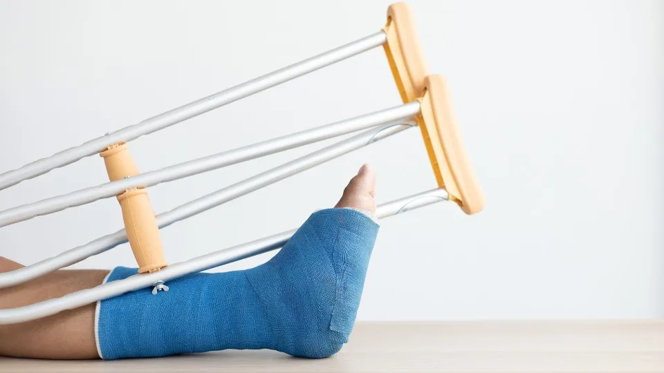 Se muestra un apierna escayolada y unas muletas