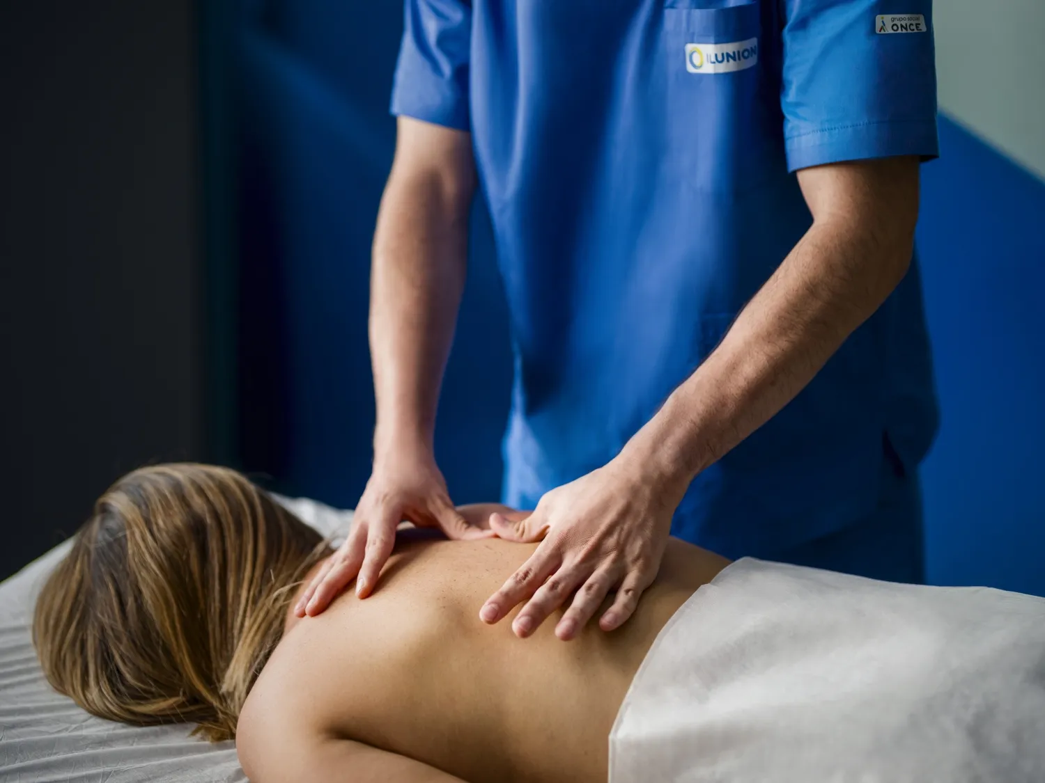 Un profesional de ILUNION aplica un masaje a una paciente