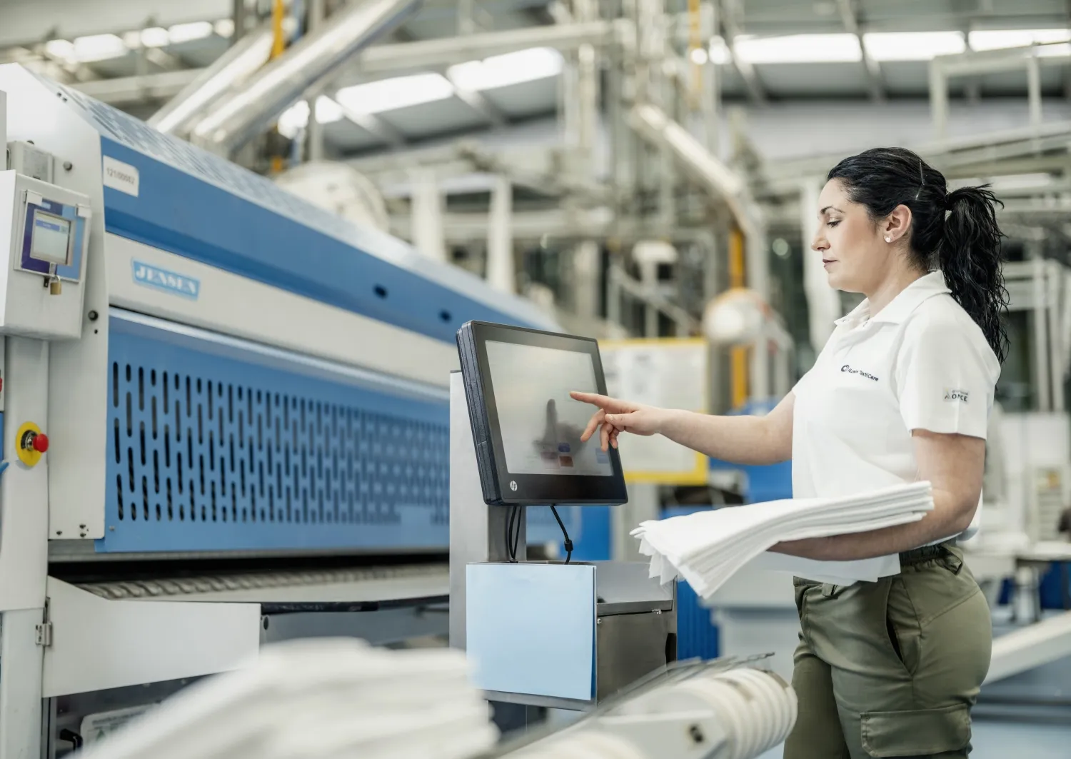 Una trabajadora de ILUNION TextilCare maneja uno de los equipos de procesado textil la compañía
