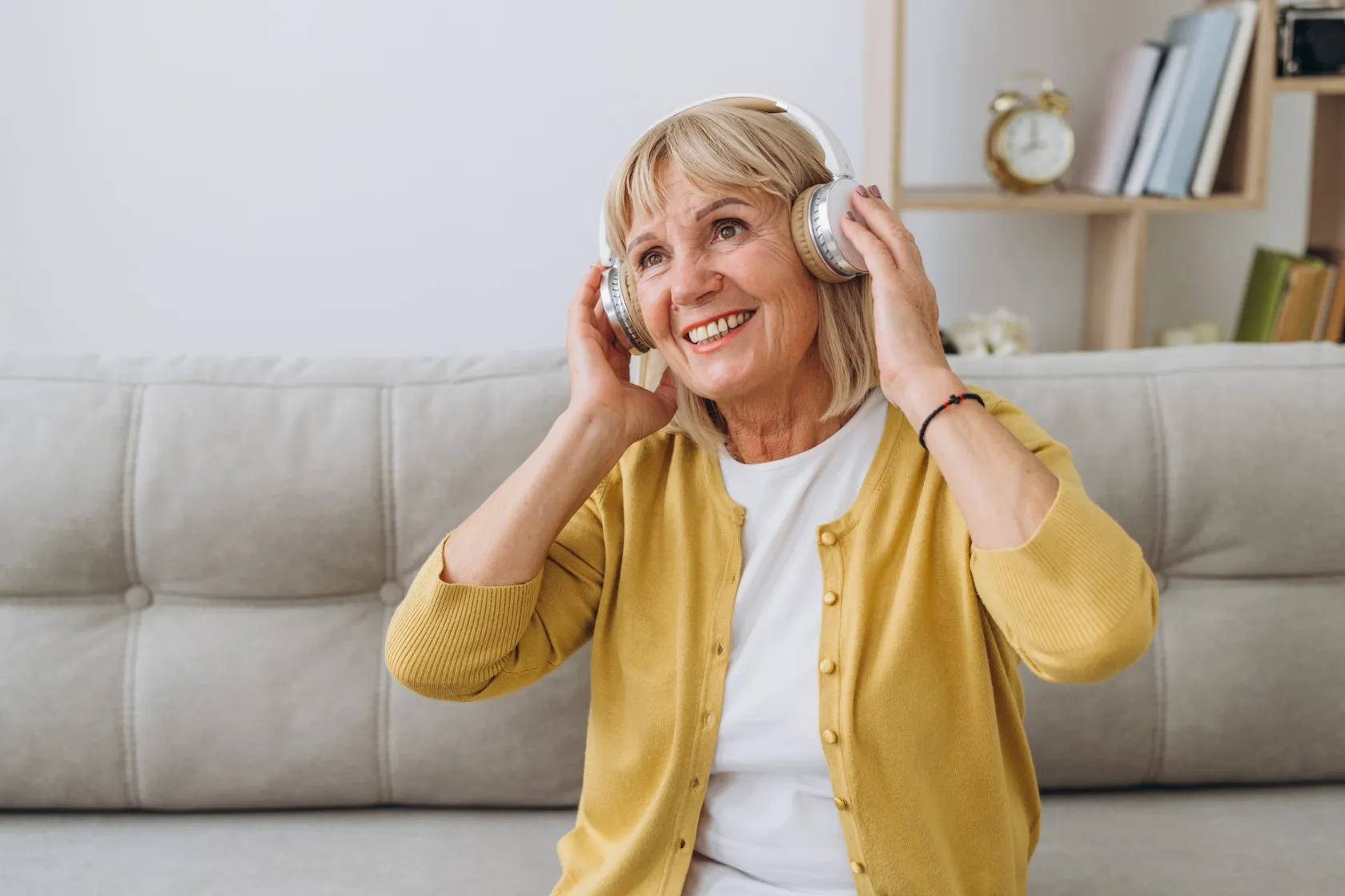 Una mujer escucha sonriente algo a través de unos auriculares