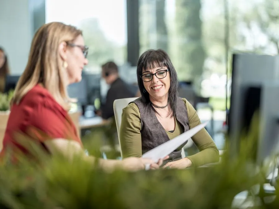 Dos mujeres en una oficina comparten información de manera distendida