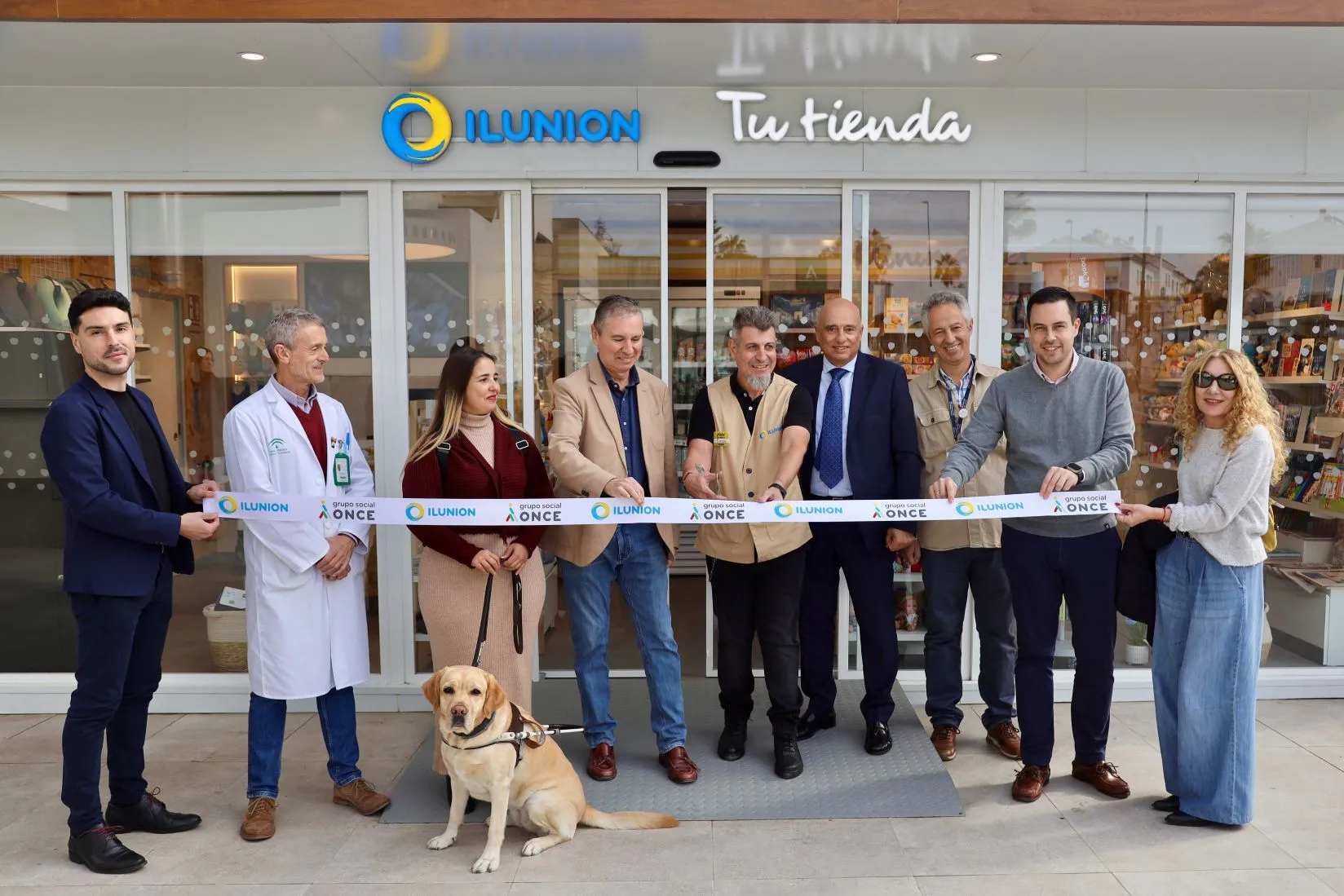 Fotografía de familia en la entrada de la tienda en el momento de cortar la cinta inaugural