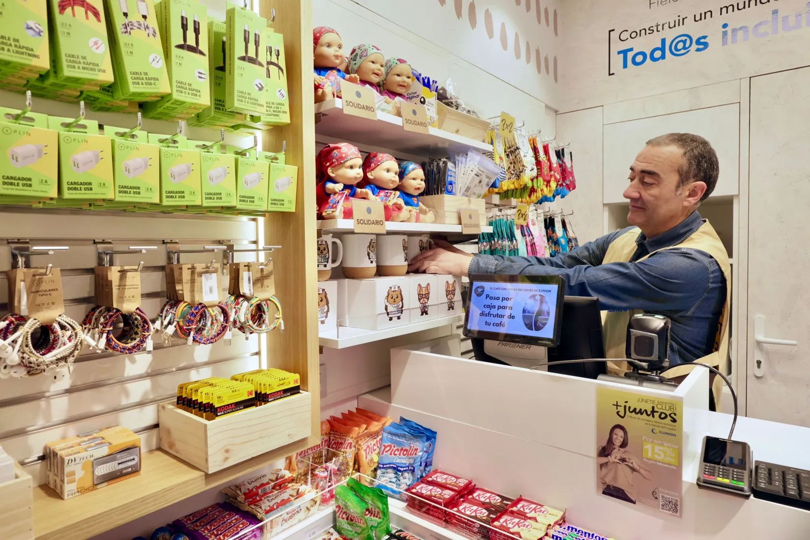Uno de los trabajadores coloca producto en una de las estanterías ubicadas junto a la caja registradora de la nueva tienda de ILUNION en el HUCA