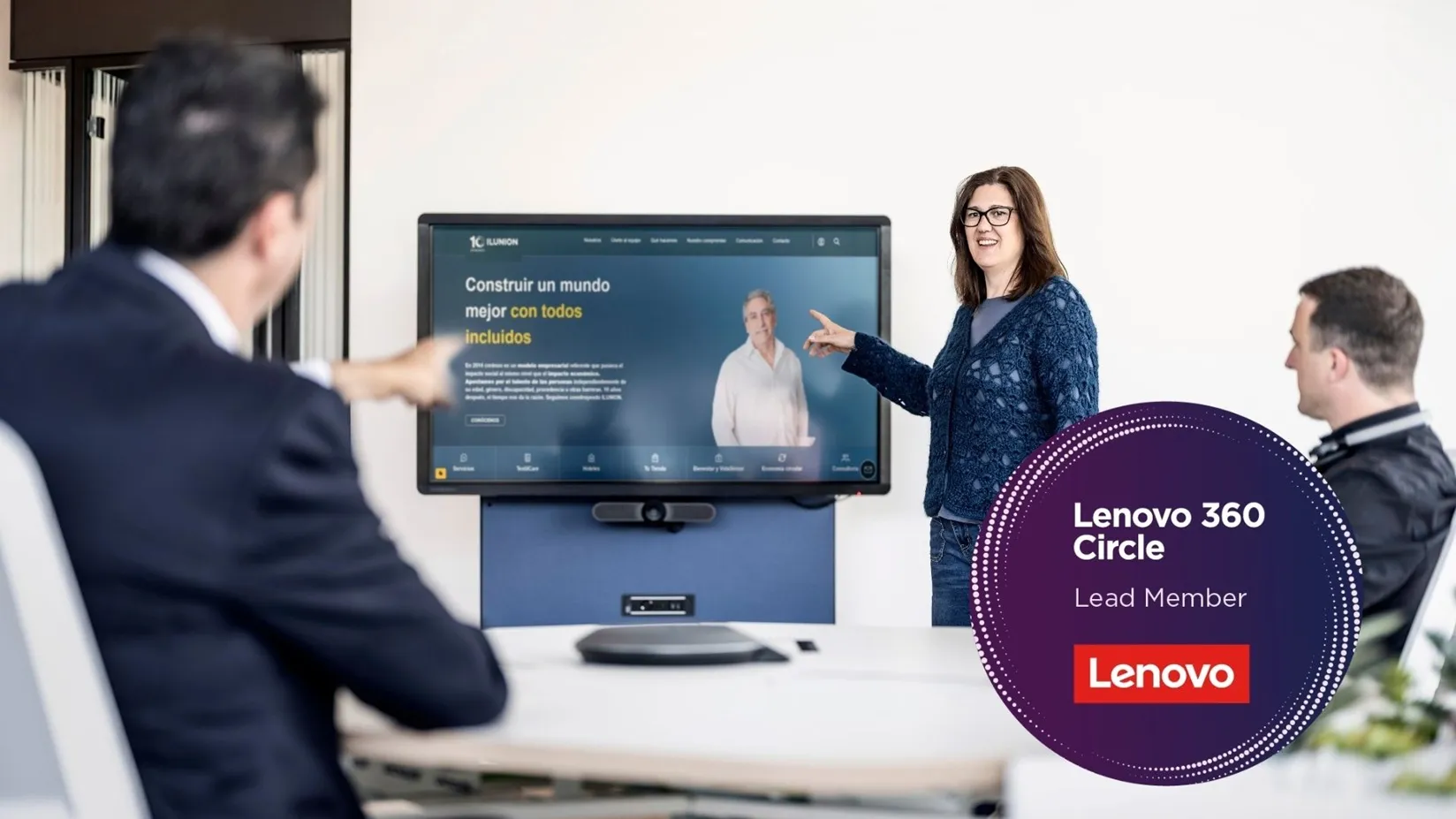 Fotografía de dos hombres y una mujer, frente a una gran pantalla con la web de ILUNION. En la parte inferior derecha, el sello del nivel Lead de Lenovo Circle 360