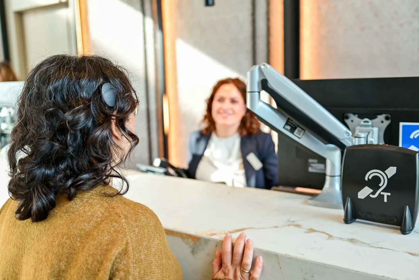 Una mujer usuaria de implante coclear, en la recepción de un hotel ILUNION equipado con bucle magnético