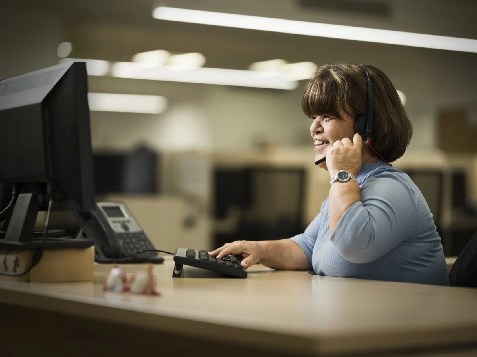 Una trabajadora de ILUNION Contact Center BPO en su puesto de trabajo atiende una llamada