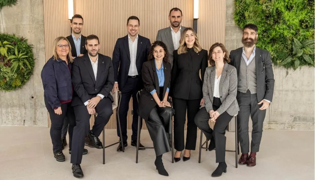 grupo de trabajadores trajeados sobre un fondo corporativo con plantas y luces