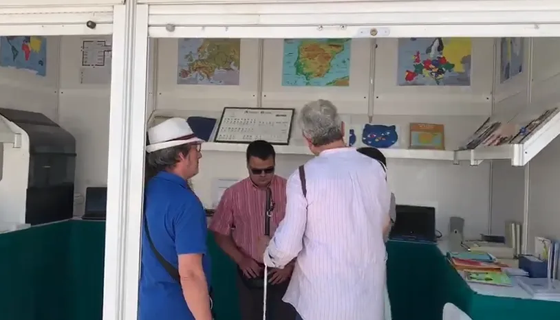 Dos personas visitan la caseta de la ONCE en la Feria del Libro 2019