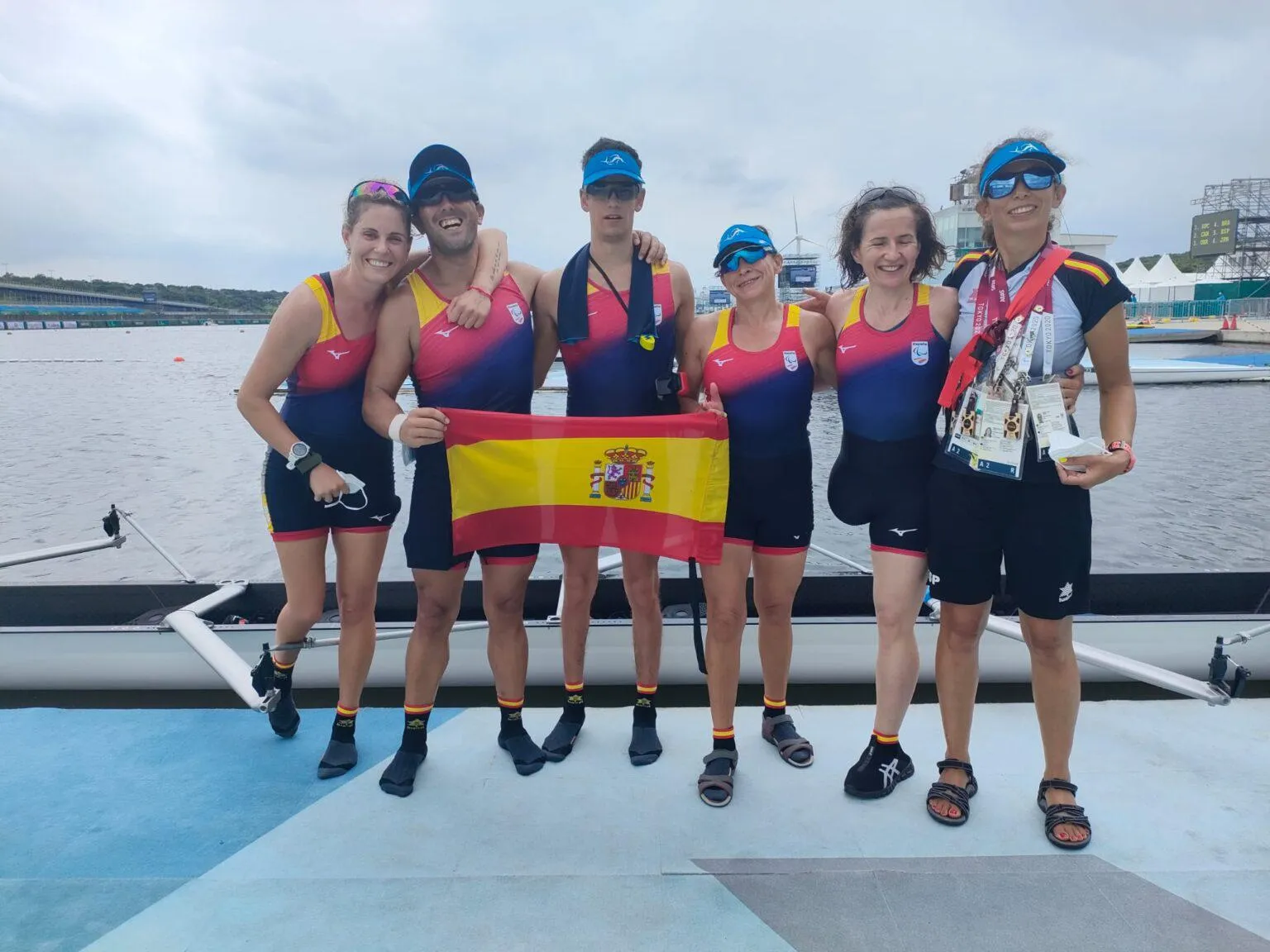 Fotografía de familia del equipo paralímpico español de remo sosteniendo la bandera española