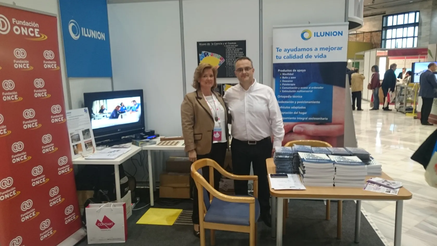 María del Carmen Fernández, de la Dirección de Accesibilidad de Fundación ONCE, y Andrés Cenamor, técnico de accesibilidad de ILUNION, en el estand de ambas entidades instalado en Contart 2016