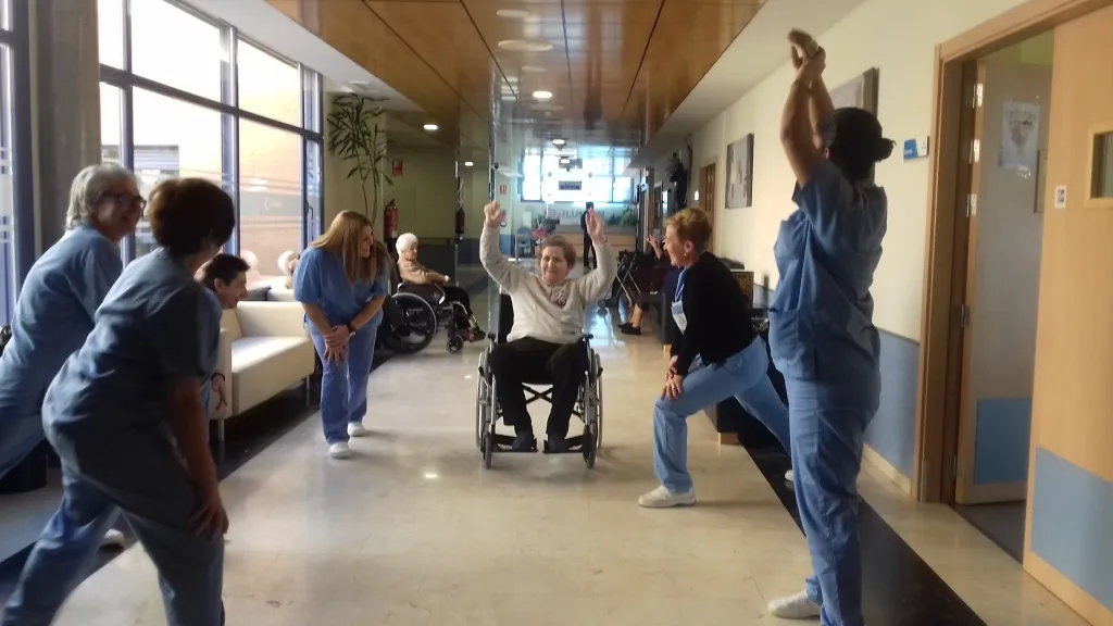 Trabajadores y usuarios realizan ejercicios de calentamiento.