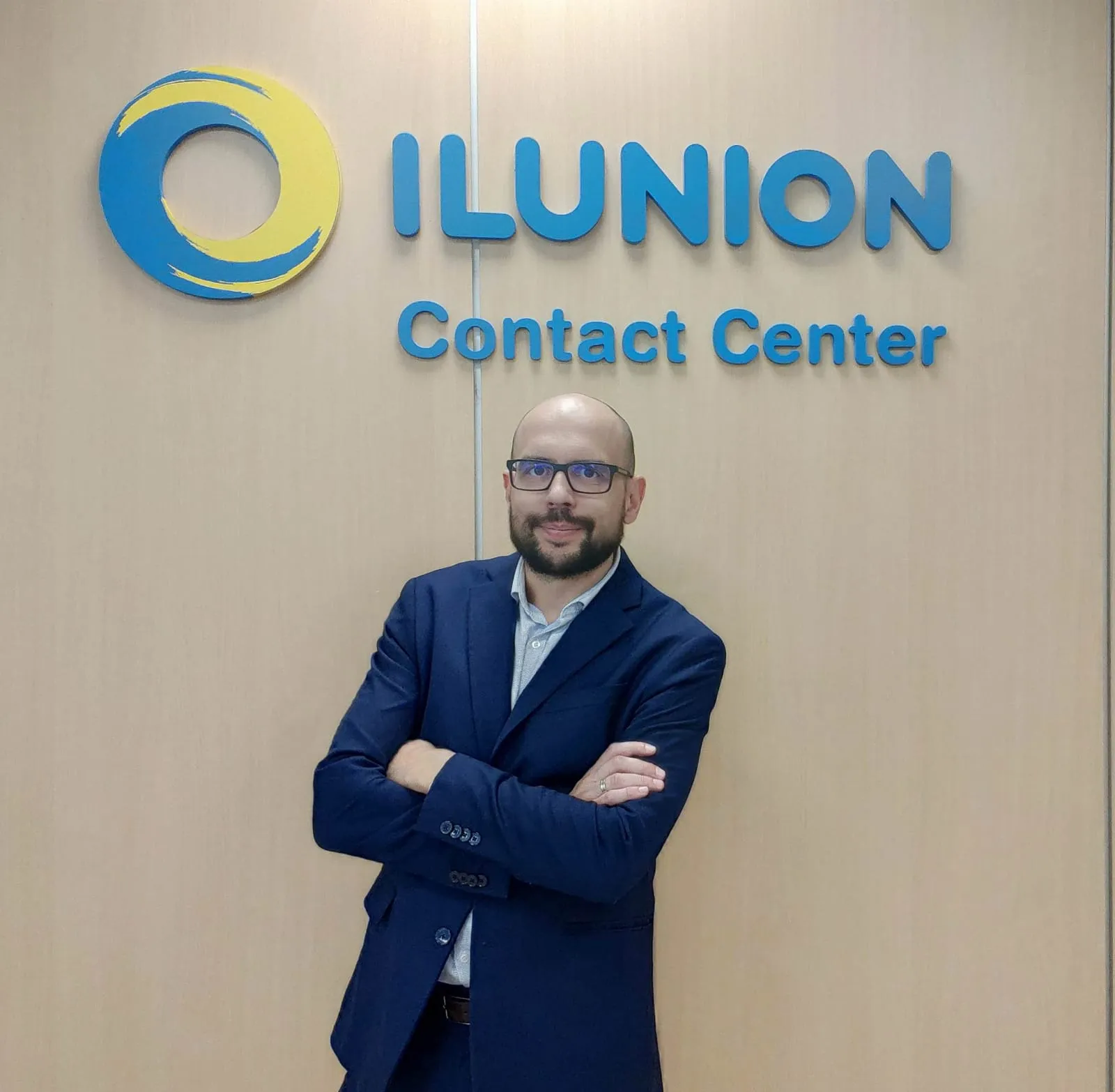 Fotografía en la que aparece Alejandro Mateo Romo y detrás aparece el logotipo de ILUNION Contact Center