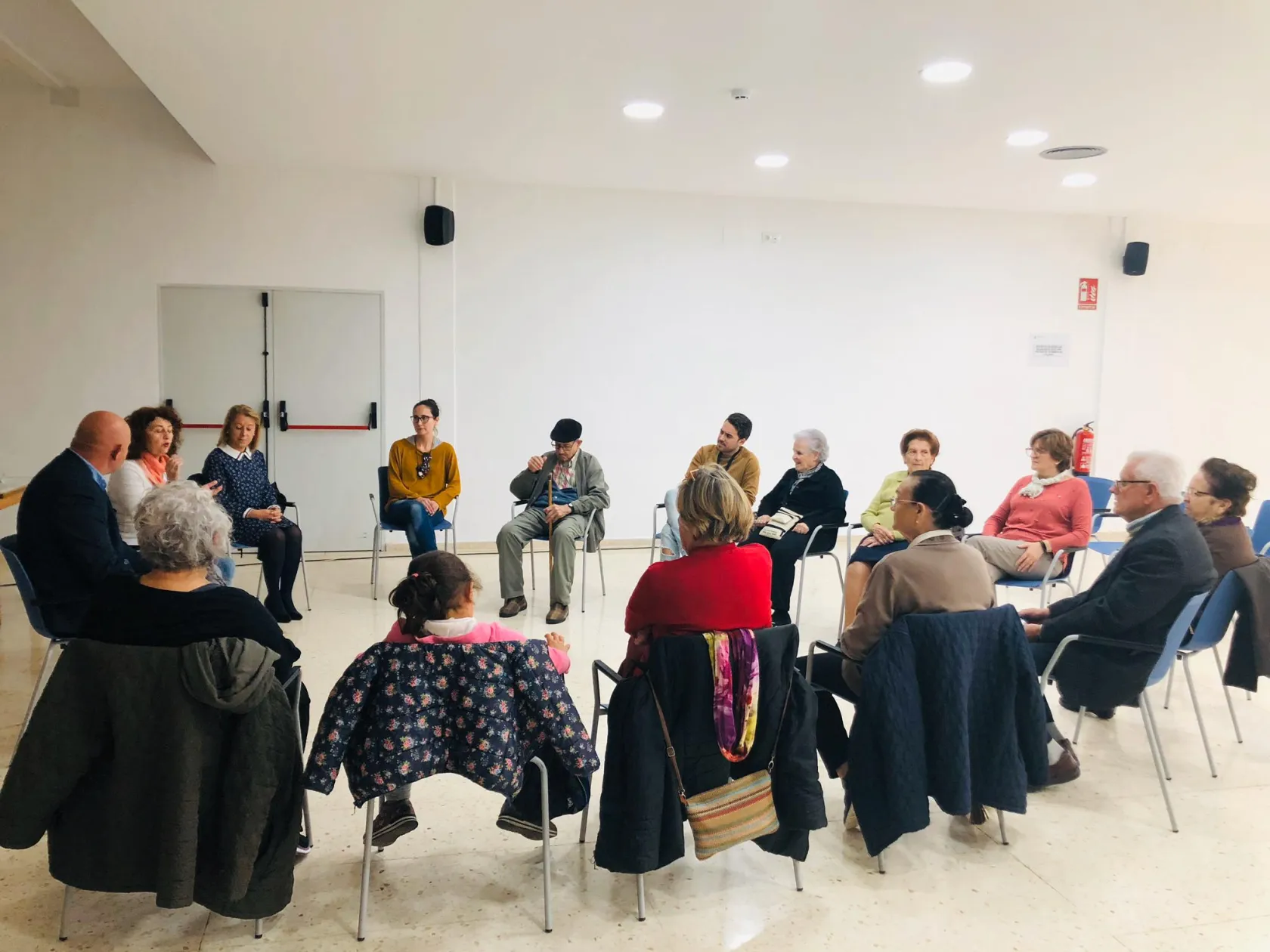 Fotografía durante el taller en la que aparecen los asistentes sentados cada uno en una silla conformando un círculo
