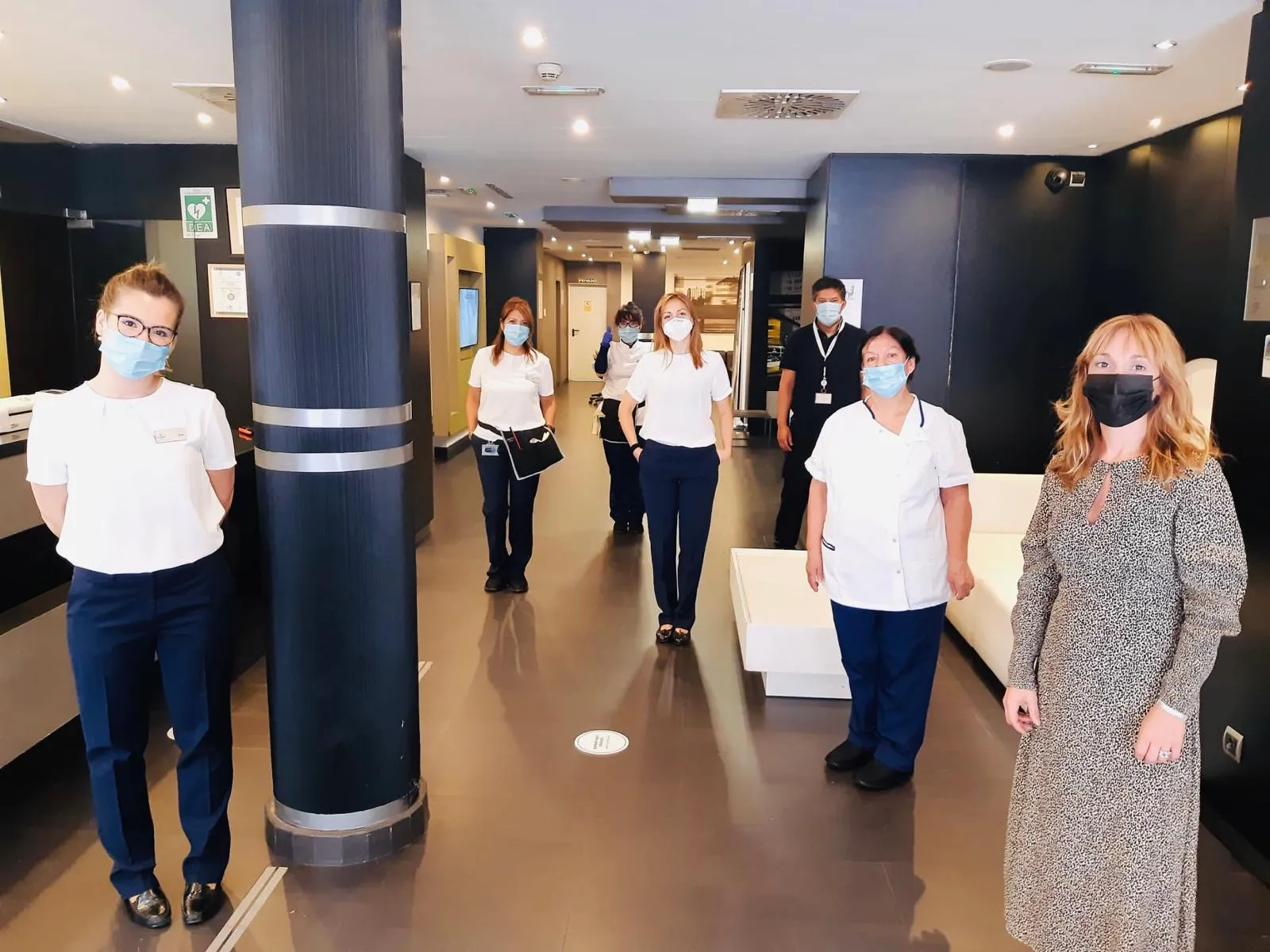 Imagen de los trabajadores del ILUNION Almirante en la entrada del hotel con EPI, mascarillas y respetando las distancias de seguridad 