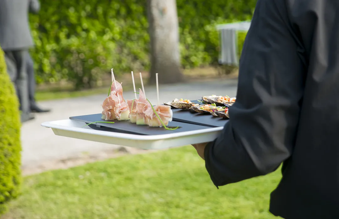 Camarero de espaldas llevando una bandeja con catering de ILUNION