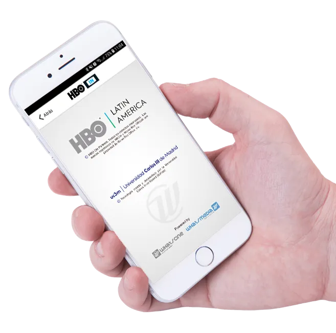 Imagen de una mano que sostiene un teléfono móvil. En su pantalla aparece la siguiente información: HBO Latin America, Universidad Carlos III de Madrid y el logotipo de Whatscine