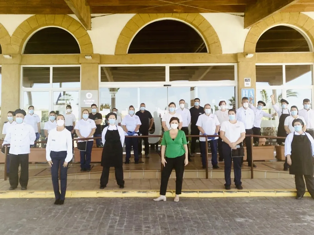 Imagen de los trabajadores con la distancia de seguridad y los EPI en la puerta del hotel 
