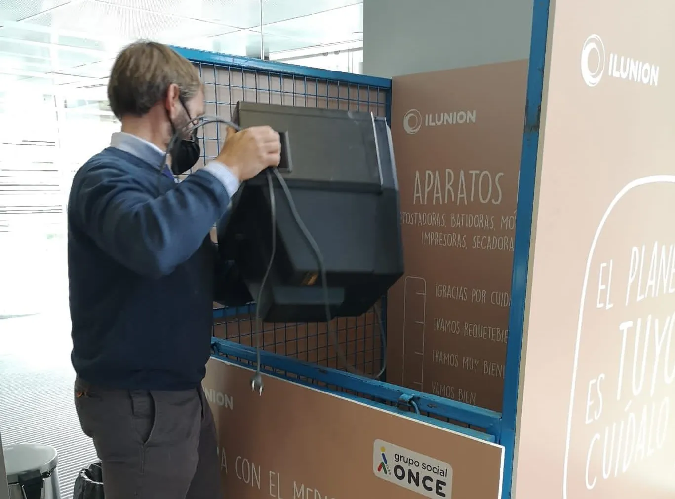 Imagen de un trabajador de ILUNION depositando una televisión en el contenedor 