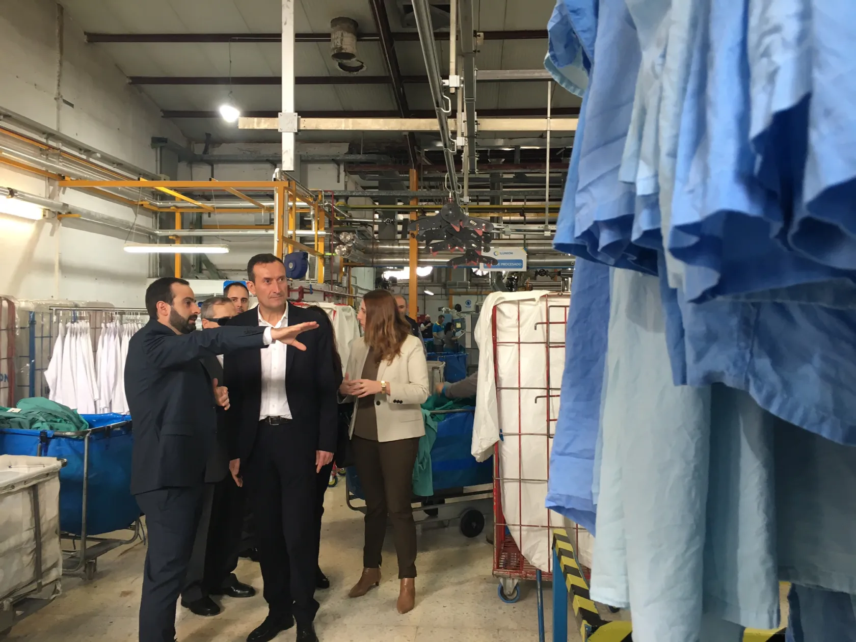 El alcalde de Elche, Carlos González, en la lavandería de ILUNION recibiendo explicaciones sobre el funcionamiento de la planta